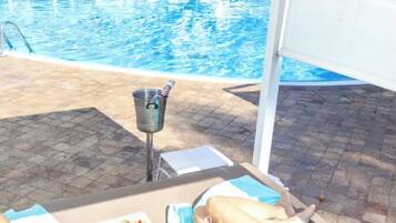 Un área junto a la piscina con sillones, una mesa de comedor con comida y una pileta.
