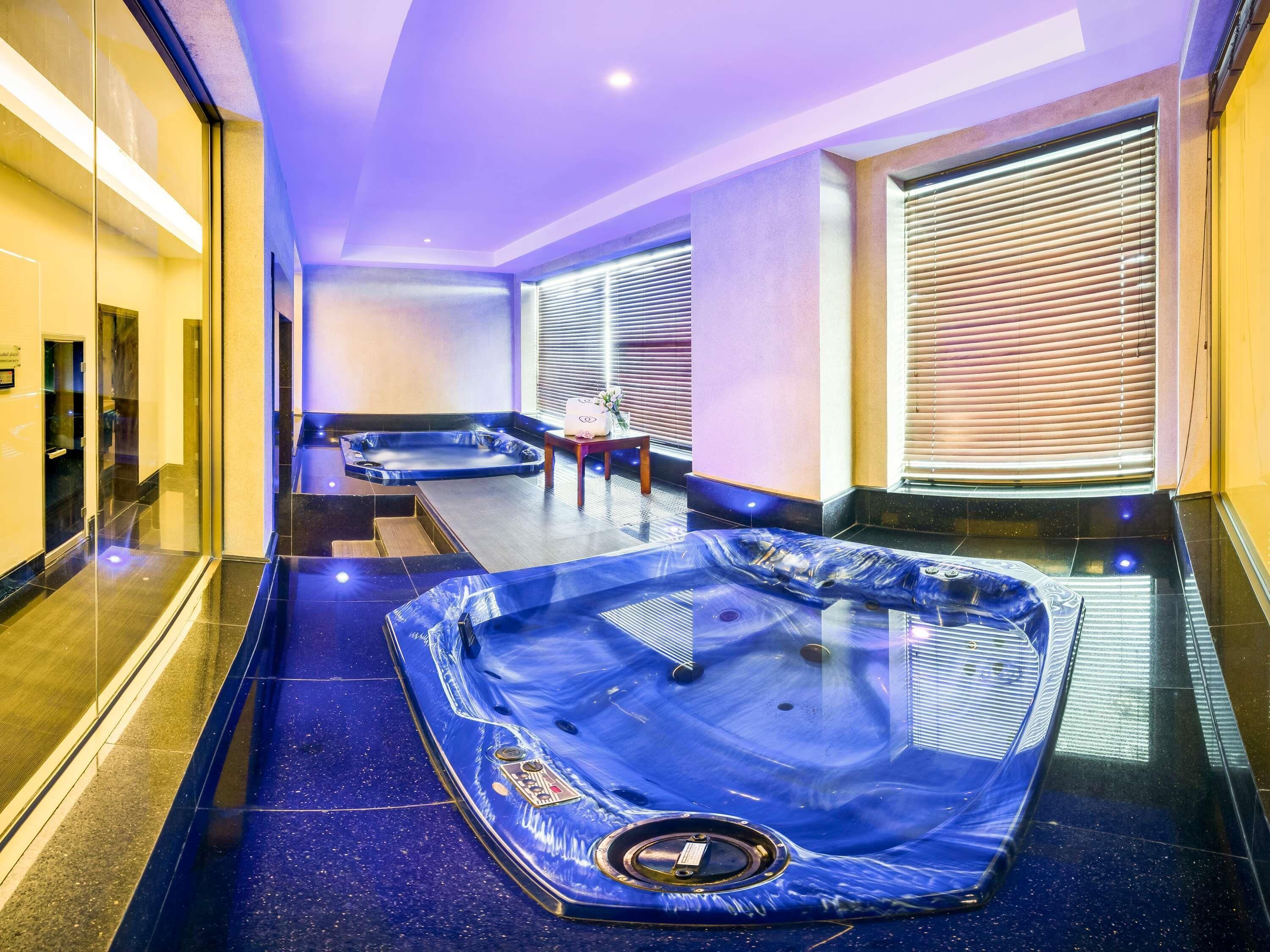 Un área de spa con dos jacuzzis, un mostrador de recepción y un ventanal con persianas.