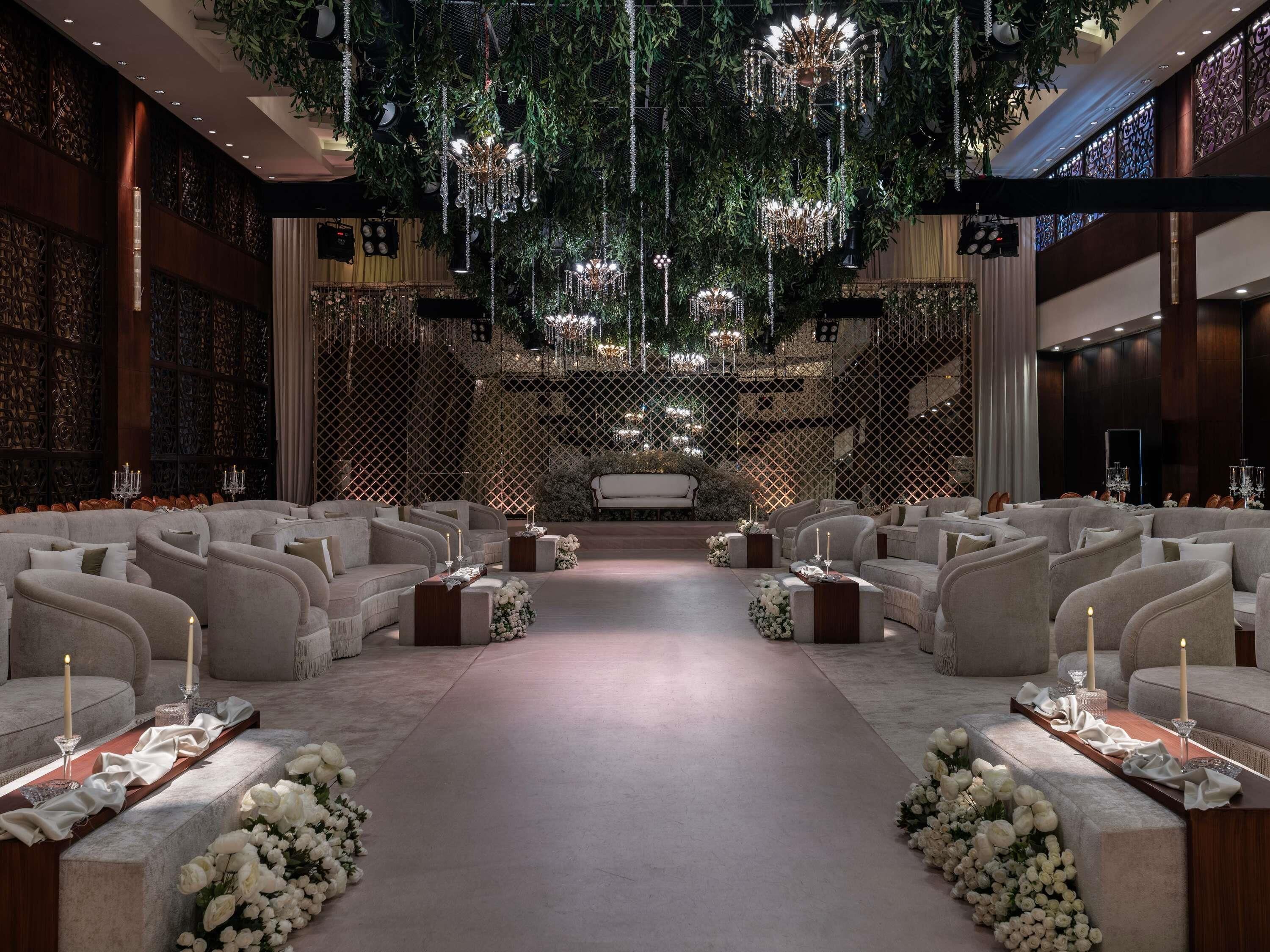 A formal indoor setting with tiered seating, chandeliers, and floral arrangements.