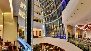 A multi-level hotel lobby with a glass atrium, seating areas, and a staircase. - Sofitel Al Khobar The Corniche (Al Khobar)