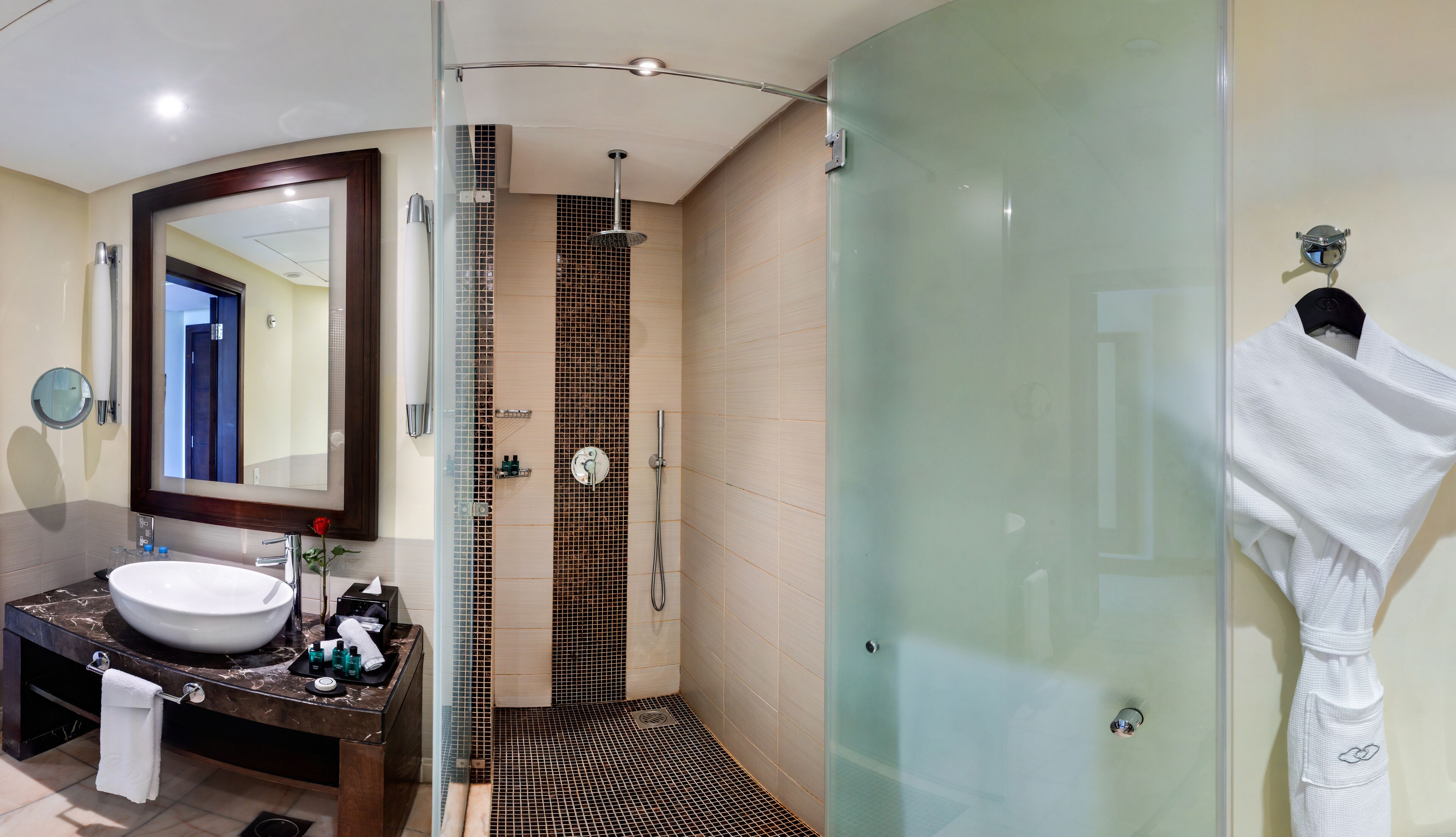 Un baño moderno con un espejo grande, un lavabo, una ducha y cabina de ducha con paredes de vidrio.