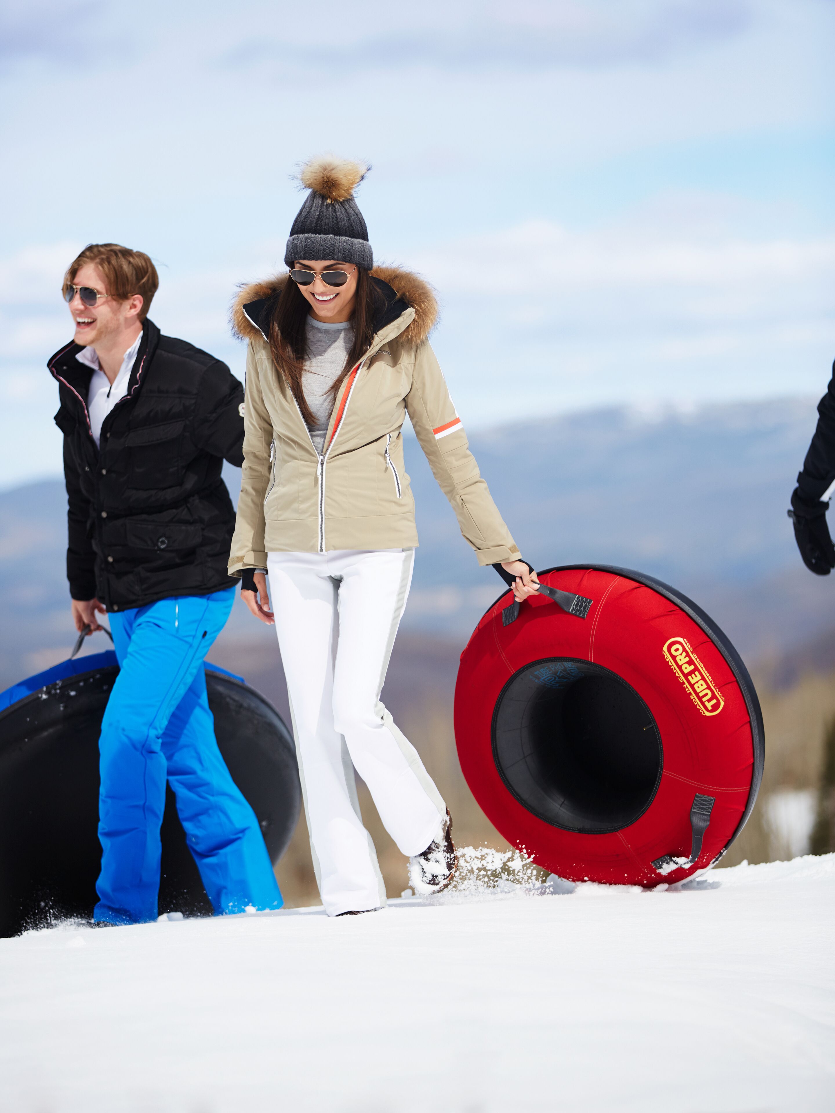 Zwei Personen wandern im Schnee mit einem Snowboard.