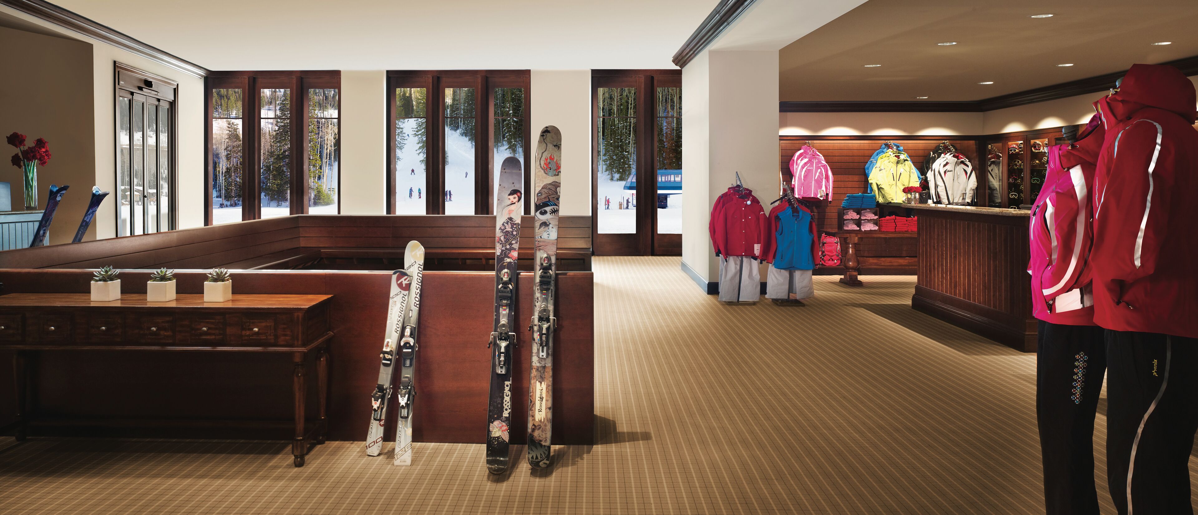 A ski resort lobby with wooden benches, ski equipment, and winter clothing displays.