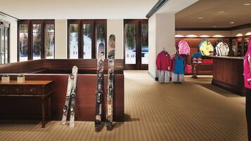 A ski resort lobby with wooden benches, ski equipment, and winter clothing displays.