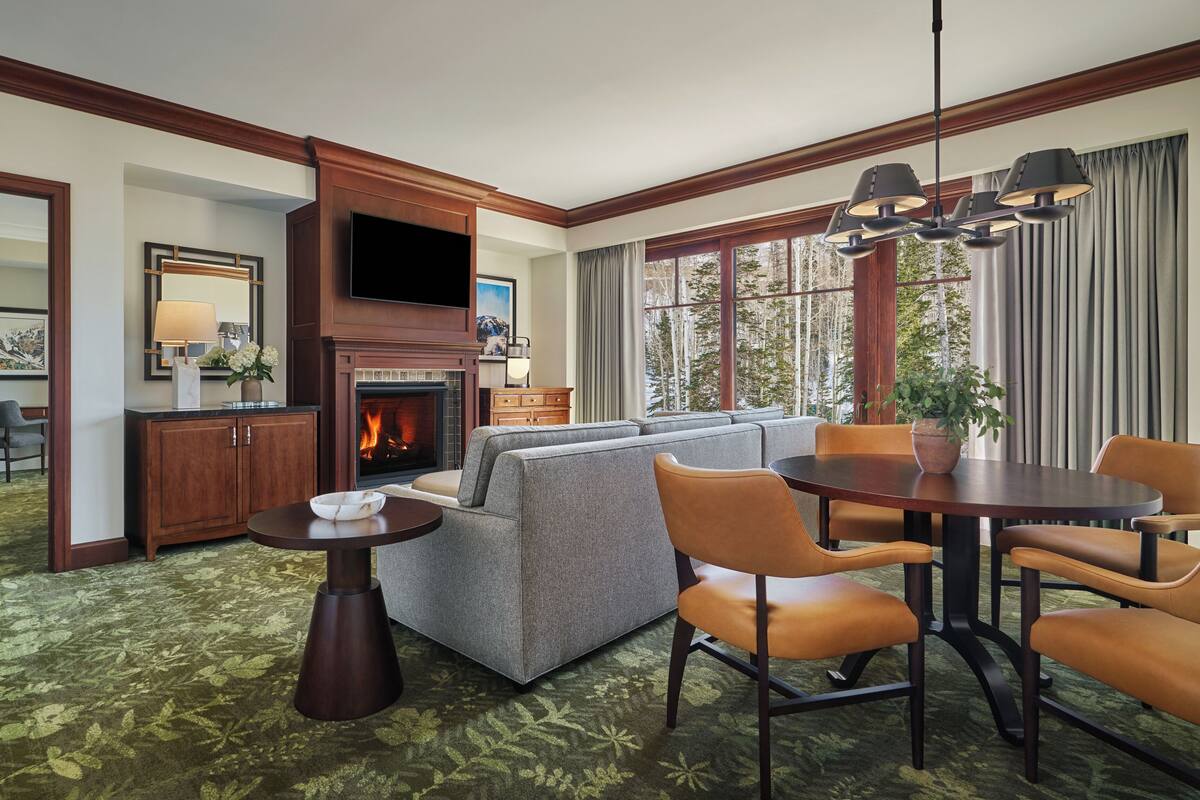 Une chambre d’hôtel avec une cheminée, un canapé, une table à manger et un téléviseur.