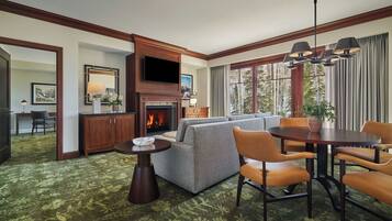 A hotel room with a fireplace, a sofa, a dining table, and a TV.