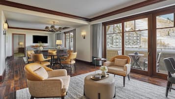 A spacious living room with a large dining table, comfortable seating, and a view of a snowy landscape through large windows.