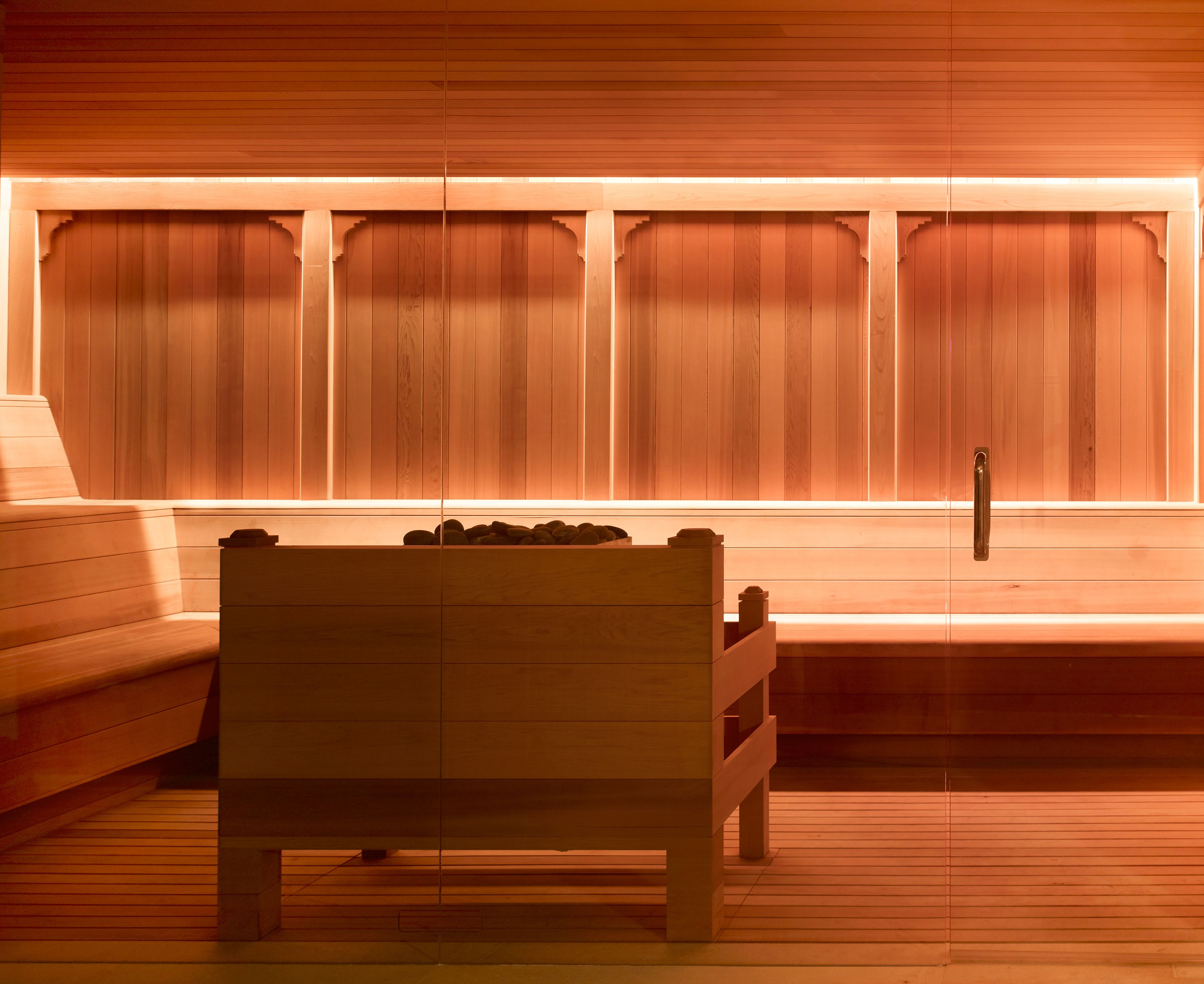Una sauna con panche in legno e una panca in primo piano.