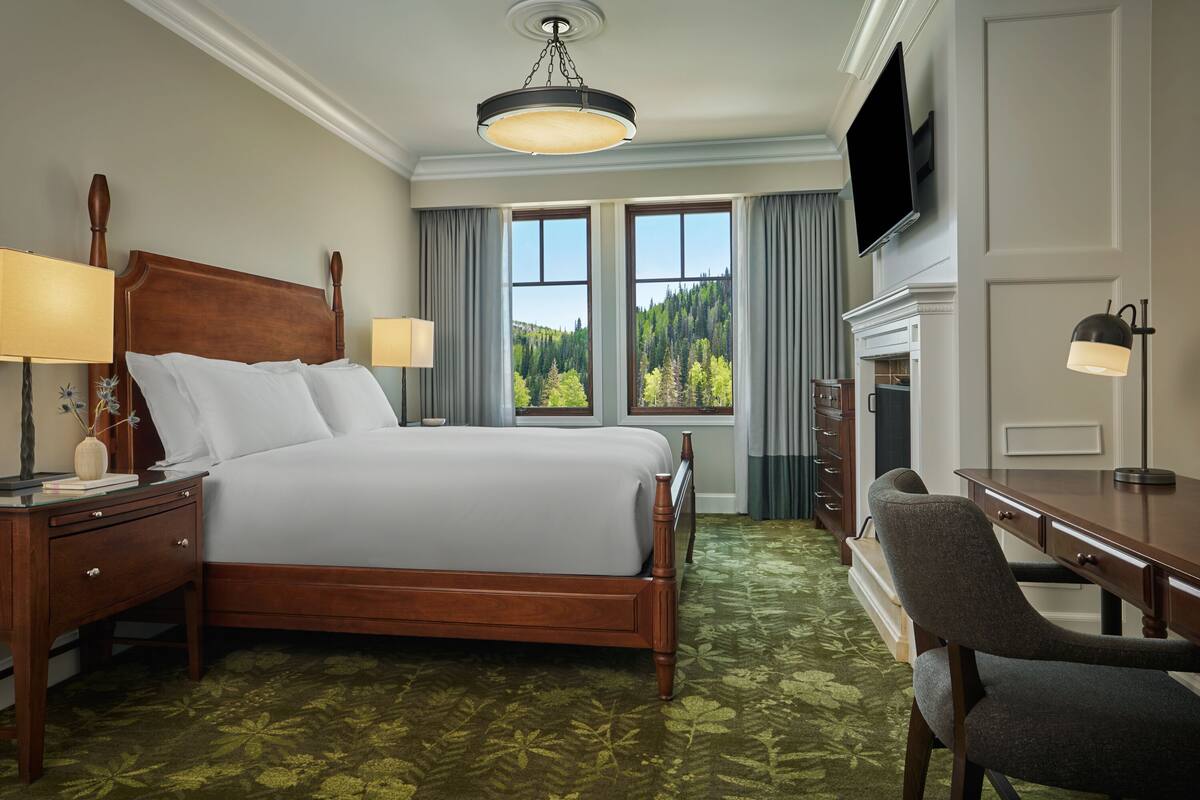 Une chambre d’hôtel avec un grand lit, un bureau, une chaise, une télévision et une cheminée.