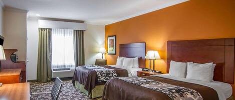 Une chambre d’hôtel avec deux lits, un bureau, une chaise et une fenêtre avec des rideaux.