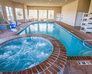Una amplia piscina interior con un jacuzzi, rodeada de ventanas y una zona de estar.