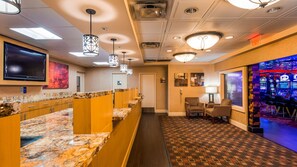 A hotel lobby with marble counters, patterned carpet, and a bar area with slot machines.
