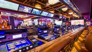 Een casino bar met verschillende speelautomaten, een barruimte met diverse drankflessen en een bord dat naar de food court wijst.