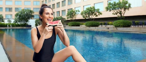 Alberca al aire libre, sombrillas en la alberca y camastros