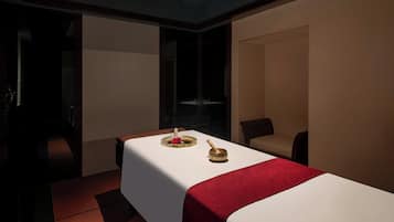 Ein Zimmer mit einer Massageliege, einem kleinen Tisch mit einem dekorativen Gegenstand und einem Stuhl.