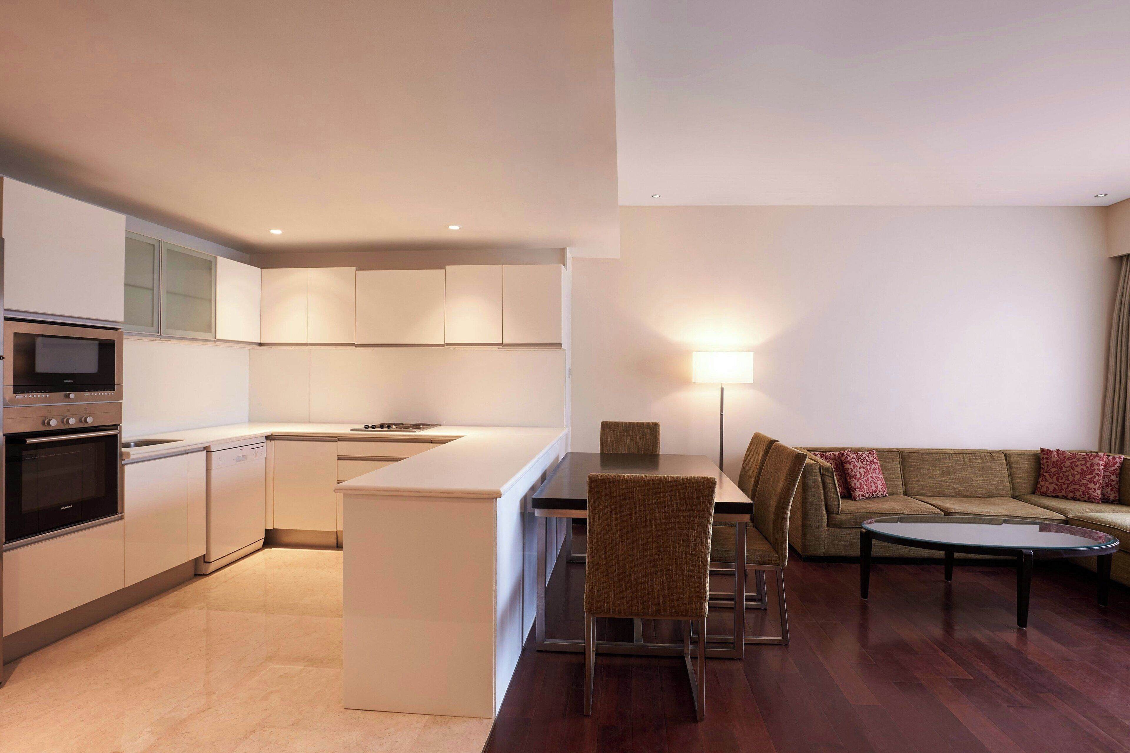 Una cocina moderna con electrodomésticos integrados y un comedor con sofá y mesa.