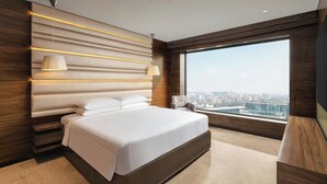 A modern bedroom with a large bed, a city view, and a unique wall design. - Courtyard by Marriott Mumbai International Airport (Mumbai)
