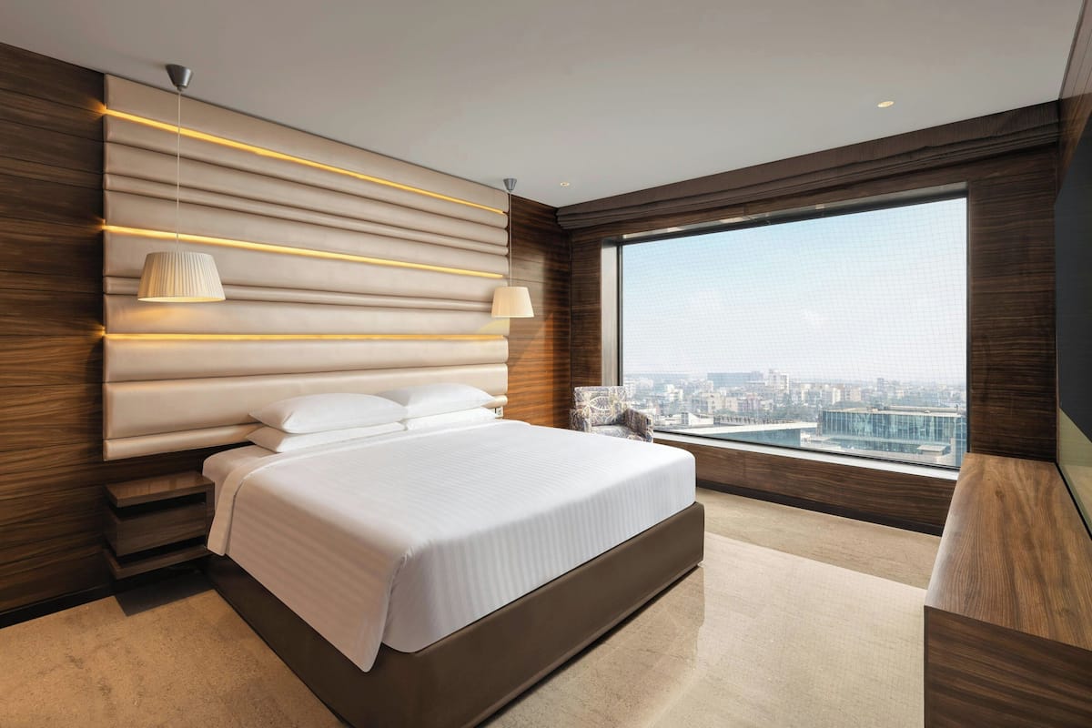 A modern bedroom with a large bed, a city view, and a unique wall design.