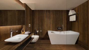 A modern bathroom with a wooden vanity, a freestanding bathtub, and a toilet.
