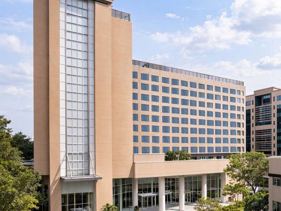 A Courtyard by Marriott hotel with a modern design, featuring a prominent glass facade, a central courtyard with seating, and a flat roof.
