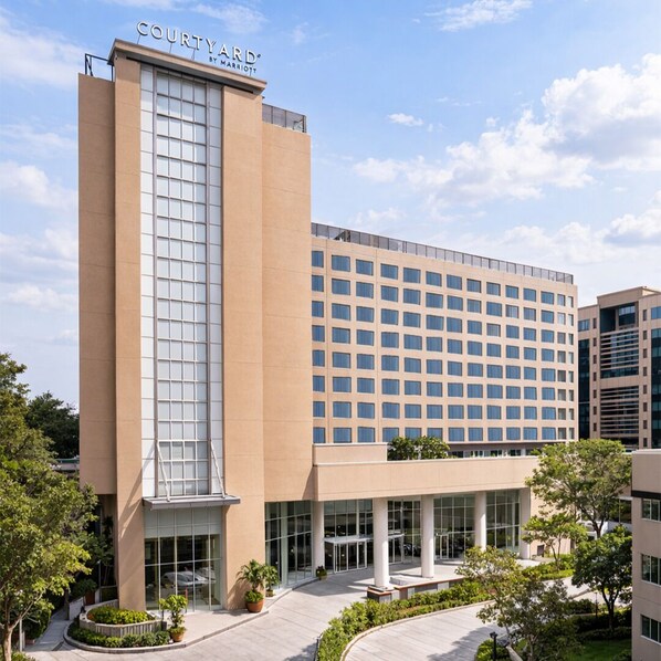 A Courtyard by Marriott hotel with a modern design, featuring a prominent glass facade, a central courtyard with seating, and a flat roof. - Courtyard by Marriott Mumbai International Airport (Mumbai)