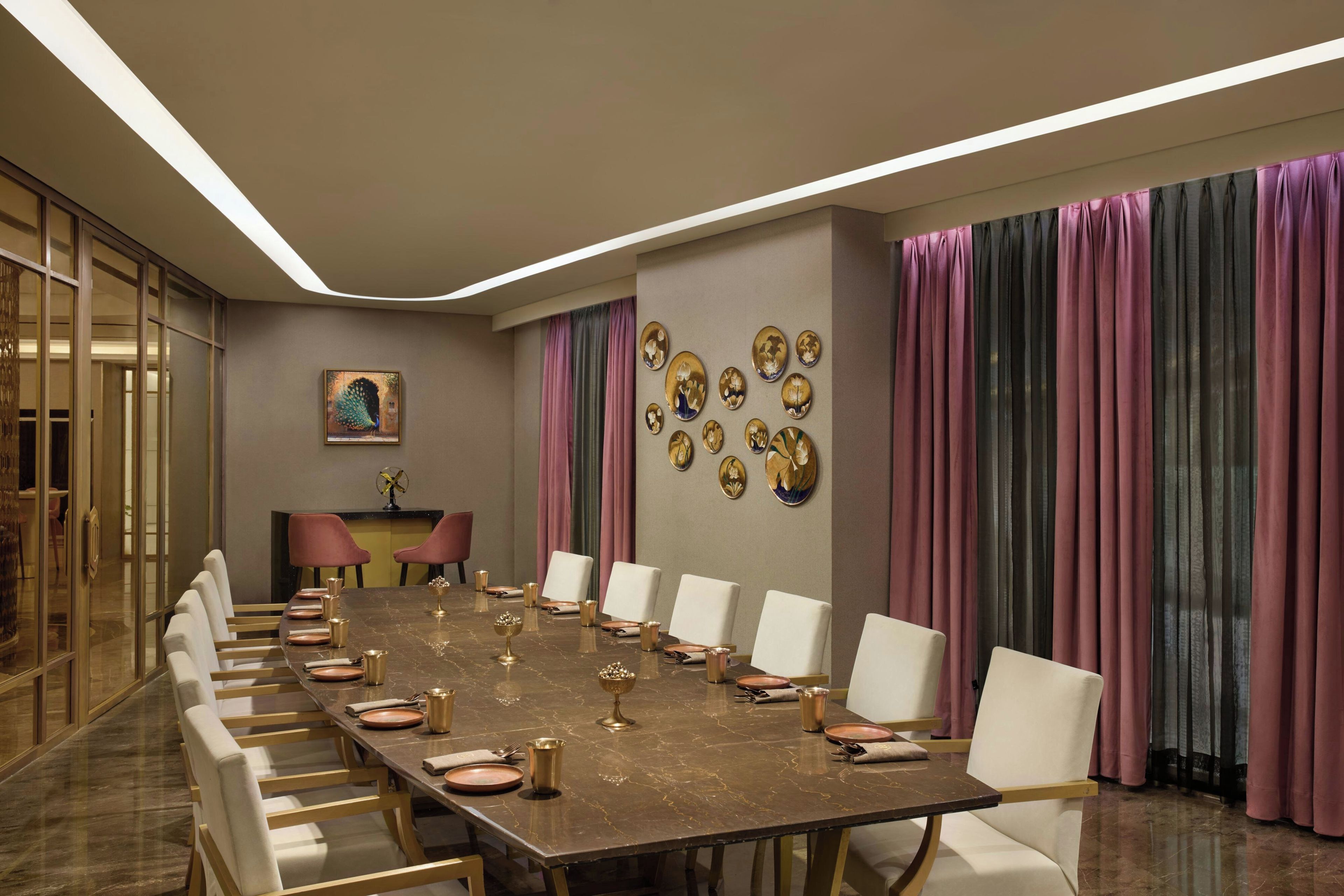 A conference room with a long table, white chairs, and a decorative wall with circular frames.