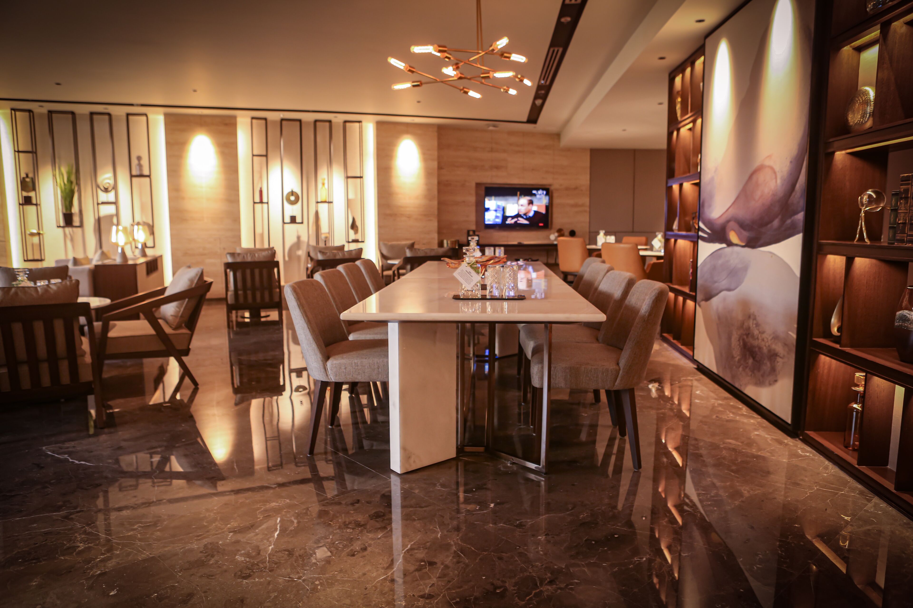 A modern dining area with a long table, comfortable chairs, and a television screen.