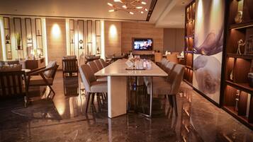 A modern dining area with a long table, comfortable chairs, and a television screen.