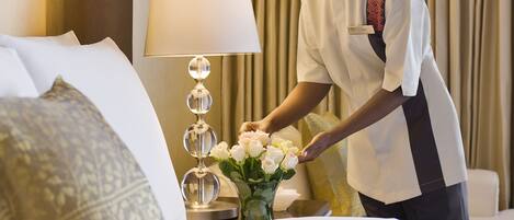 Una habitación de hotel con una cama bien hecha, una lámpara y un jarrón de flores.