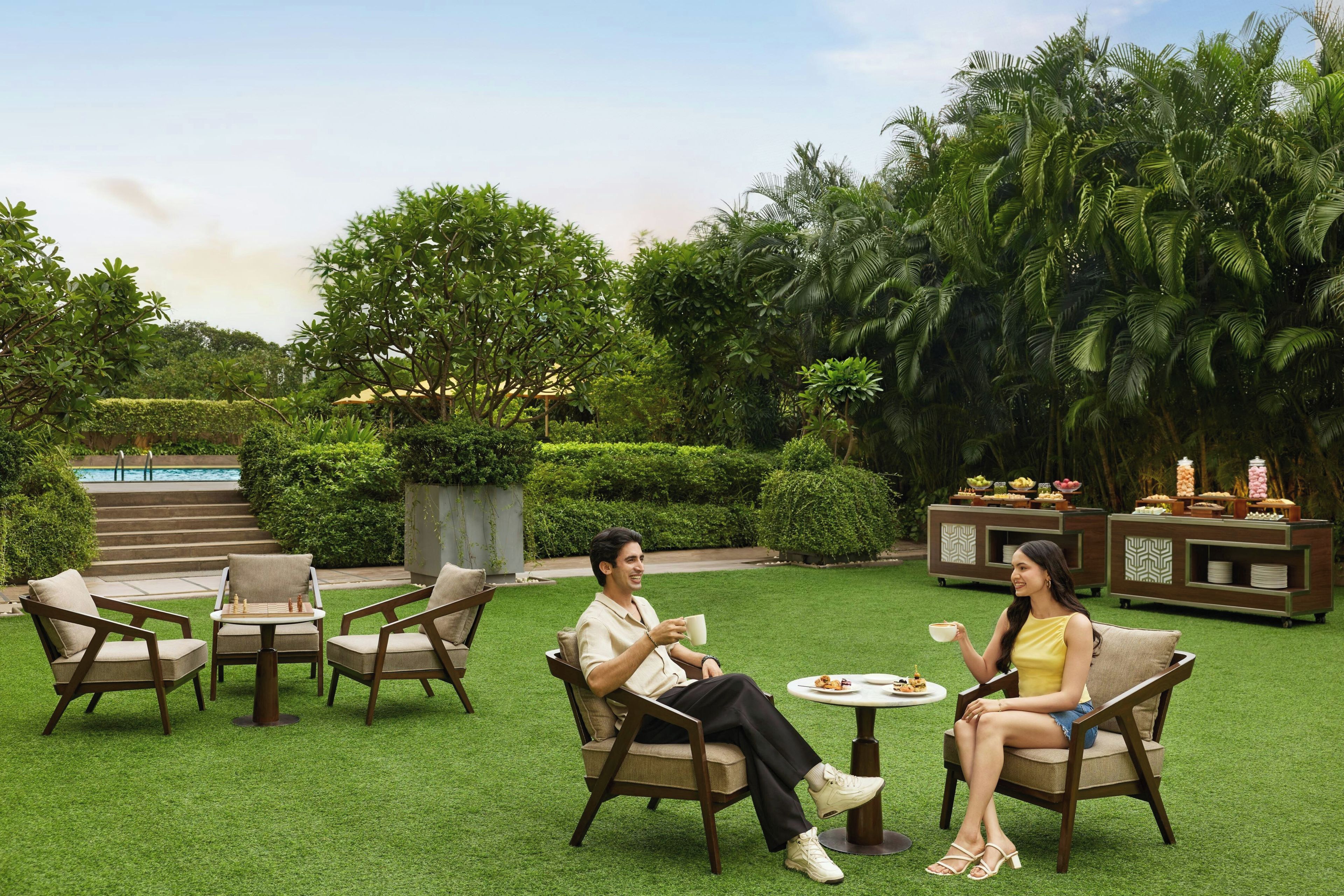 A couple seated at a table with a buffet in a lush garden setting.