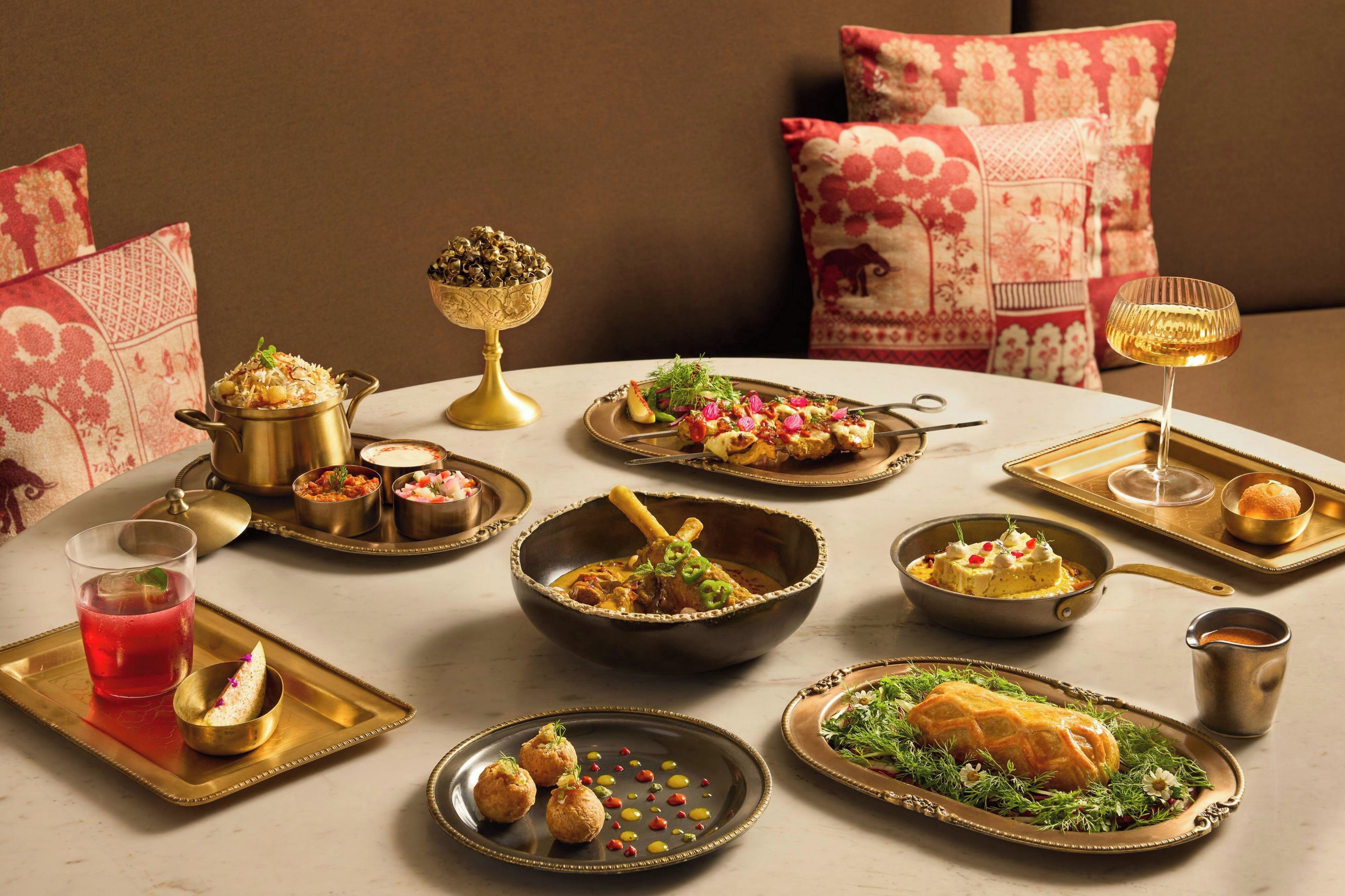 A dining table set with various dishes, including a bowl of rice, a plate of meat, and a glass of red beverage.