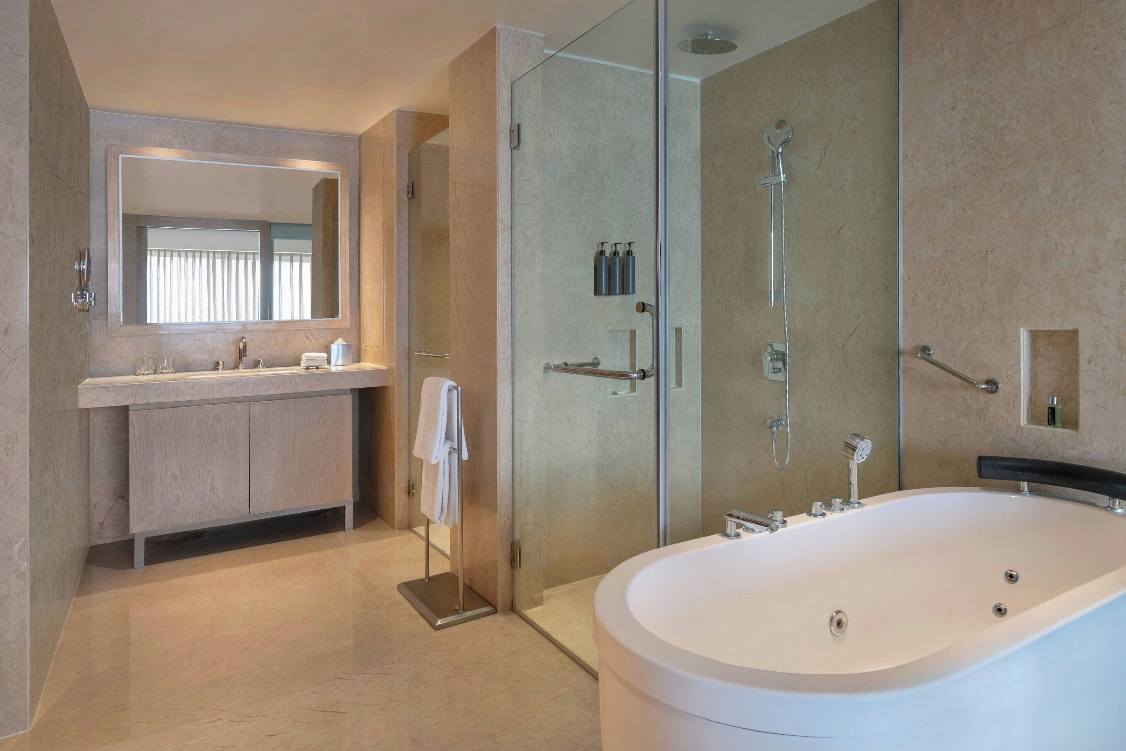 Un baño moderno con una bañera grande, una ducha con cerramiento de vidrio y un tocador con espejo.