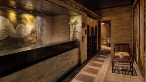 A stone-walled corridor with a wooden bench and a vase of flowers. - Courtyard by Marriott Mumbai International Airport (Mumbai)