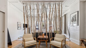 A modern living room with a wooden coffee table, two beige armchairs, and a geometric patterned rug. - The Haus on Mirror Lake (Lake Placid)