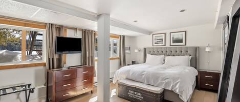 Een moderne slaapkamer met een groot bed, een televisie en een dressoir.