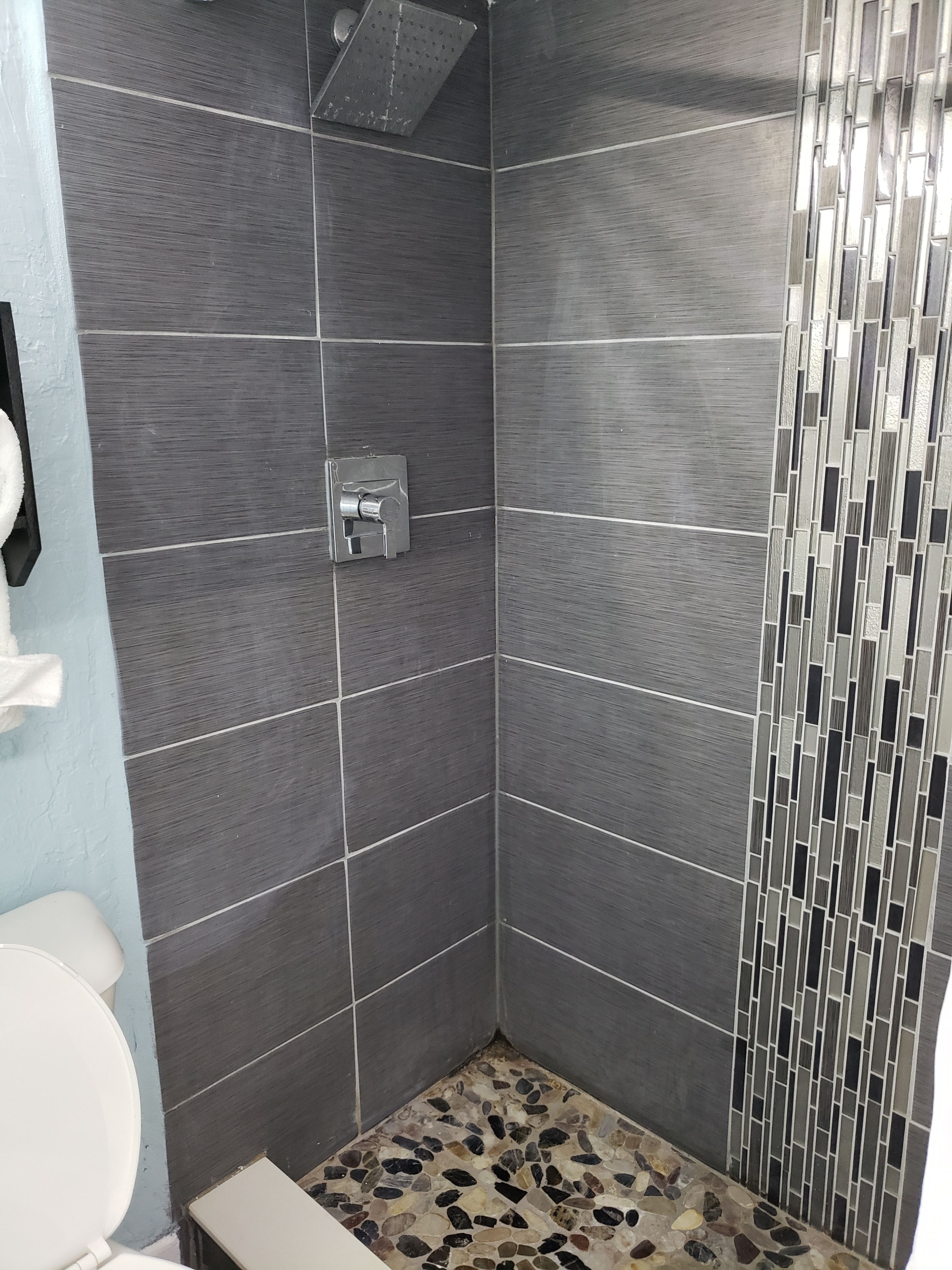 Een douche met betegelde vloer en douchekop.