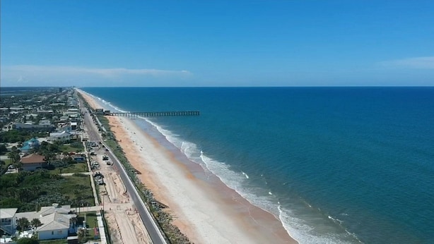 A coastal road with a beach and a pier extending into the ocean. - Topaz Motel (Flagler Beach)