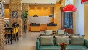 Un vestíbulo moderno con mostrador de recepción, zona de estar y área de comedor.