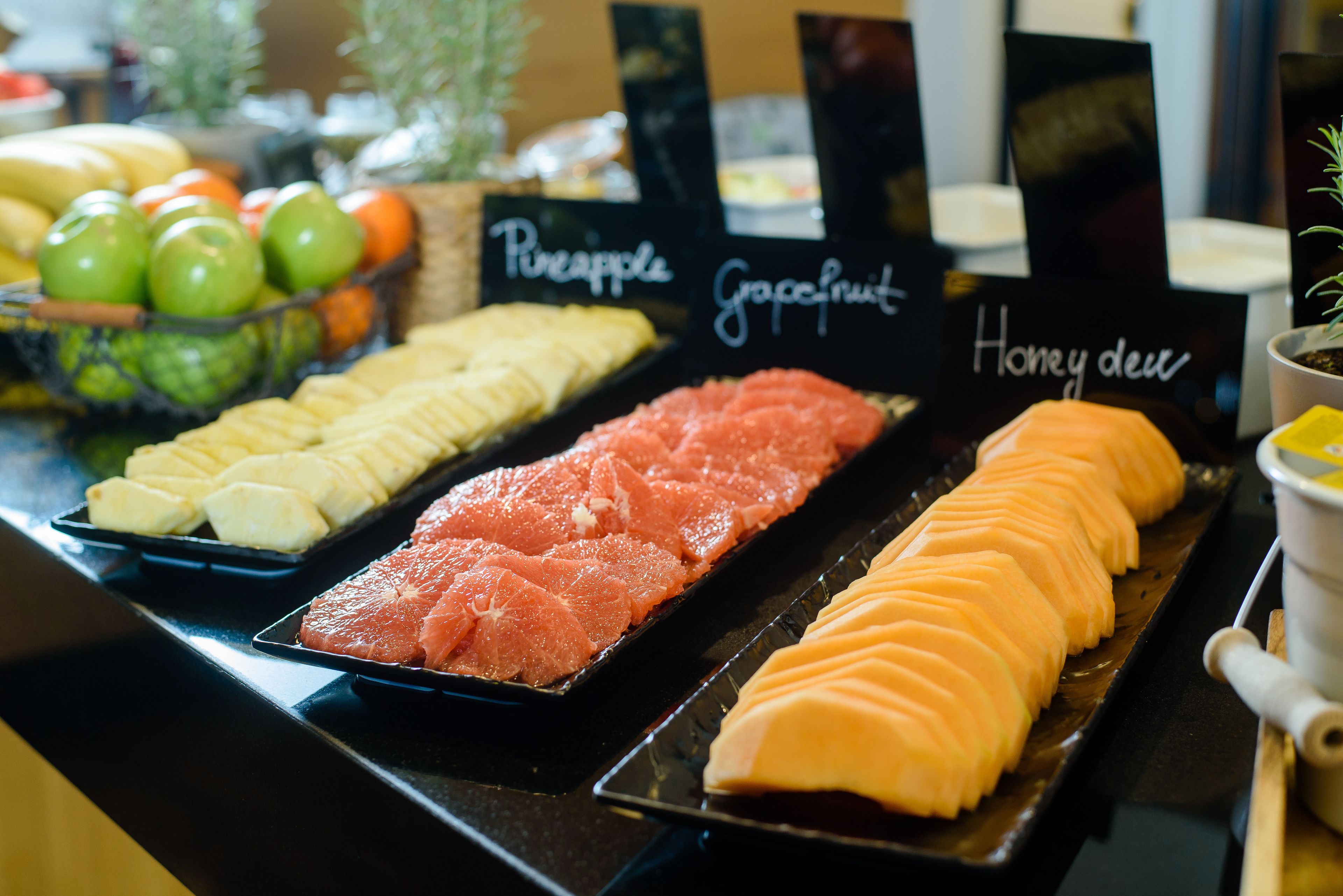 A display of fresh fruits including pineapple, grapefruit, and honeydew arranged on a counter.