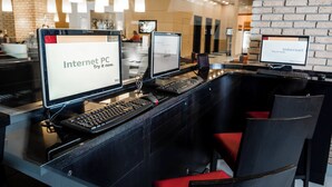 Una moderna área de recepción con varias estaciones de computadoras, cada una mostrando el letrero 'Internet PC. Pruébalo ahora'.
