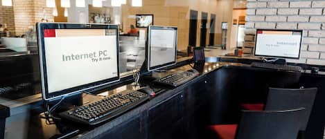 A modern reception area with multiple computer stations, each displaying 'Internet PC. Try it now.' signs.