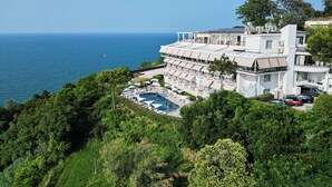 Un hotel frente al mar con piscina, varios balcones y vistas al océano.