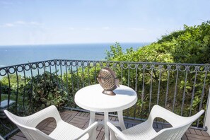 A balcony with a white table and two white chairs, overlooking the ocean. - Posillipo (Gabicce Mare)