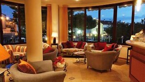 Un espacio interior bien iluminado, con amplios ventanales, una zona de estar con sofás y sillones, y una barra.