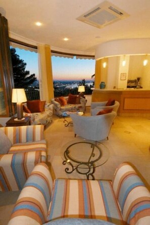 A living room with striped sofas, a coffee table, and a view of the cityscape. - Posillipo (Gabicce Mare)