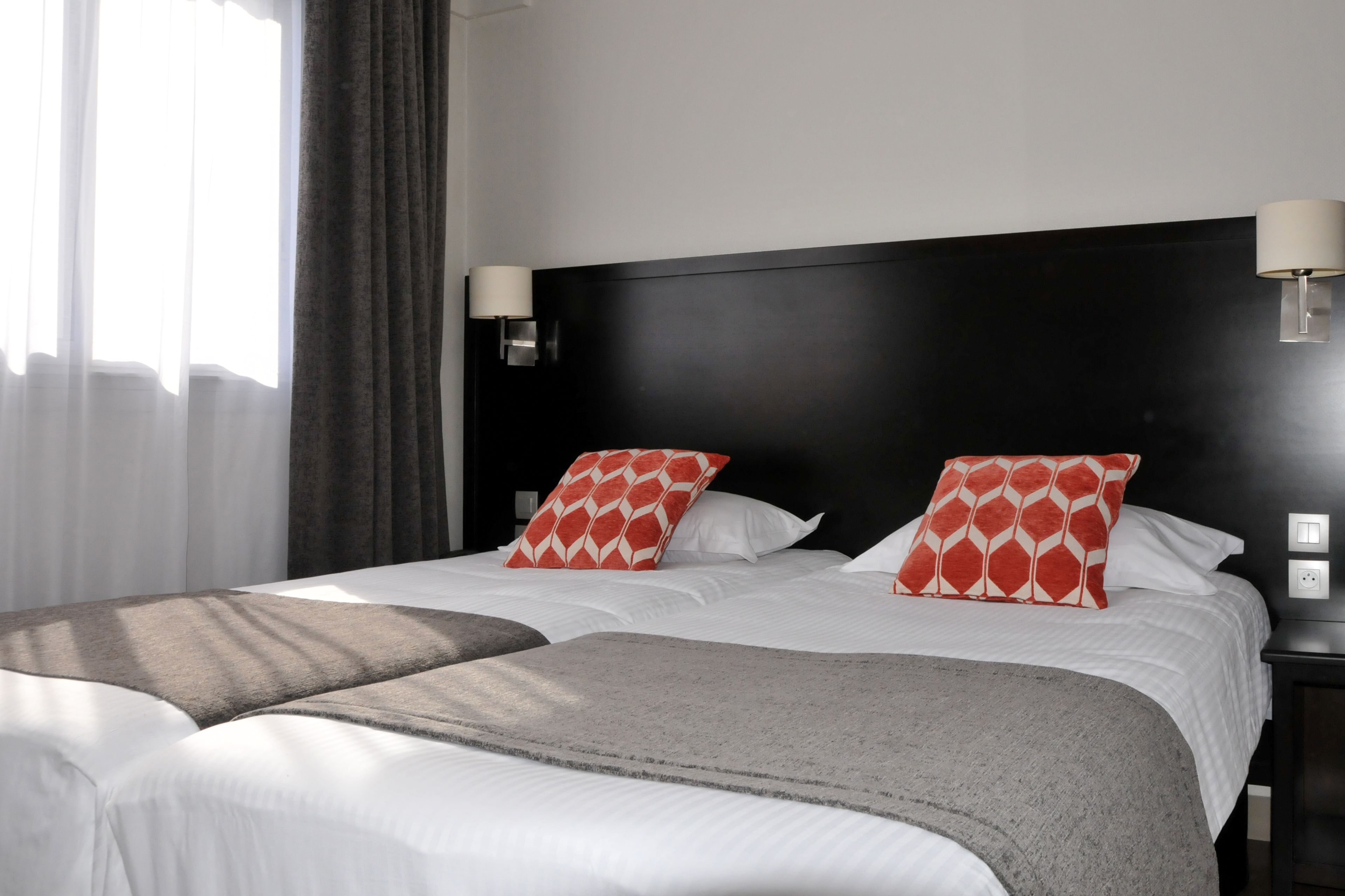 Una camera d'hotel con un letto grande, due comodini e una finestra con tende.
