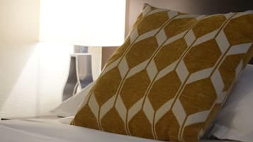 A bed with a patterned pillow and a plain pillow, a bedside table, and a lamp.