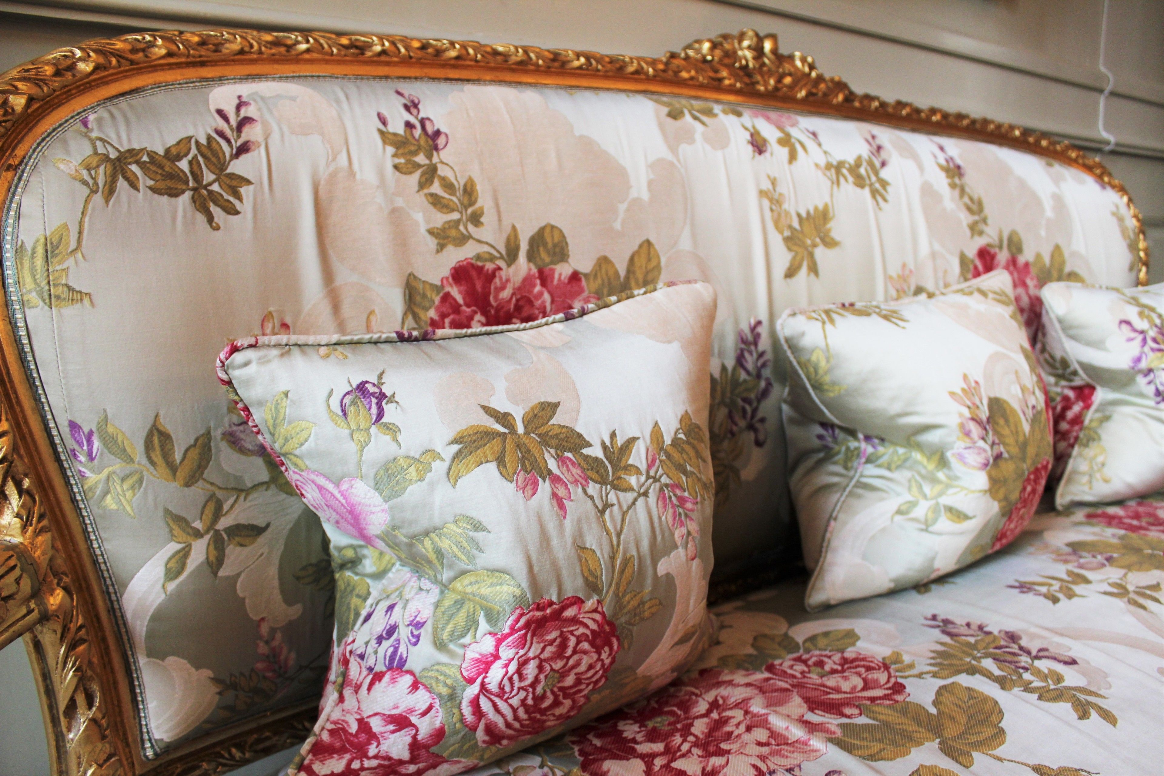 Un canapé recouvert d’un tissu à motifs floraux et doté d’une structure dorée.