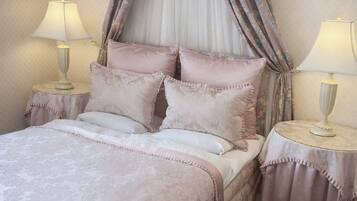 Un lit à baldaquin, deux tables de chevet avec des lampes et une moquette à motifs.