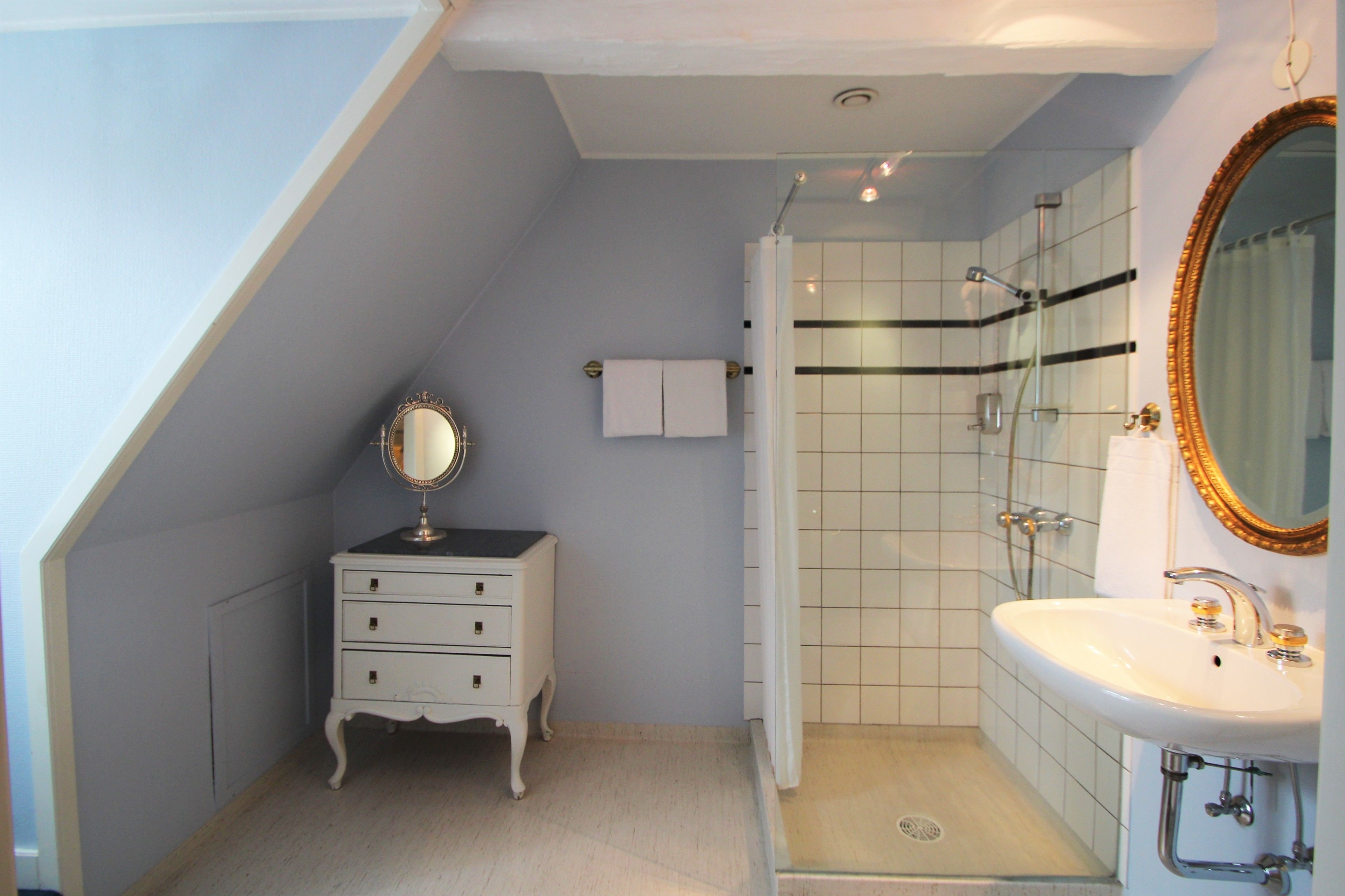 A bathroom with a white vanity, a mirror, a shower with a glass door, and a white sink.
